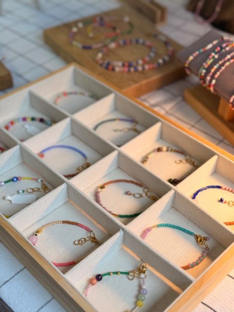 Bunte Armbänder in verschiedenen Designs in einem Holzschmuckkasten angeordnet.